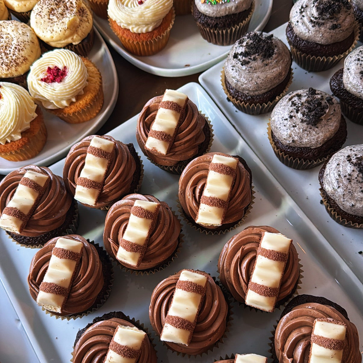 Assorted cupcakes with different flavors and designs on a tray.