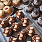 Assorted cupcakes with different flavors and designs on a tray.