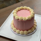Pink cake with yellow decorative icing on a white plate