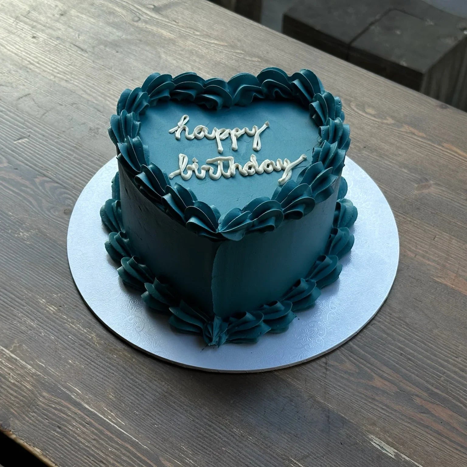 Blue birthday cake with 'happy birthday' text on a wooden table