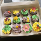 Box of cupcakes with colorful frosting and decorative elements