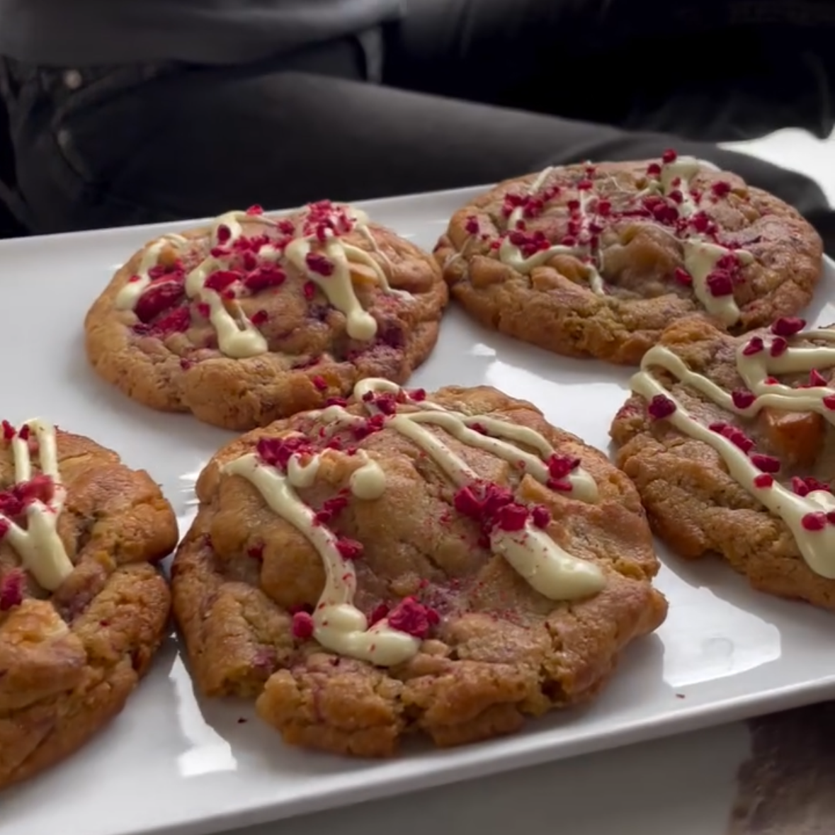 Cookies with white drizzle and red sprinkles on a white plate