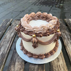 Two-tiered cake with chocolate frosting on a wooden table