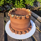Chocolate cake with gold decorations on a wooden table outdoors